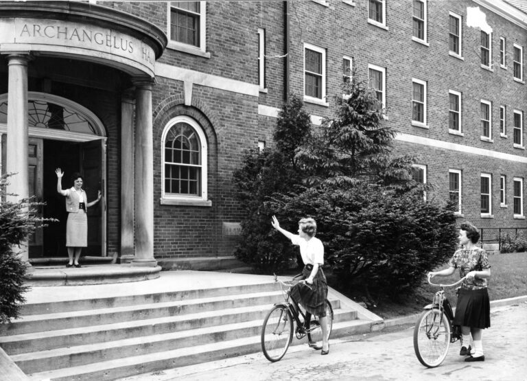 Students on bicycles outside Archangelus Hall 1950s,
